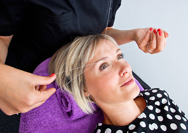 Woman undergoing threading hair removal procedure stock photo