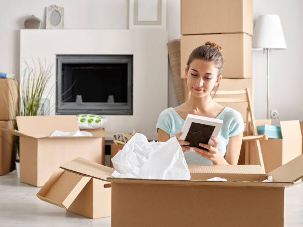 Woman unpacking cardboard boxes in new home stock photo