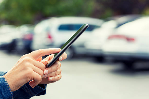 Woman uses her cell phone application connected to her car. stock photo