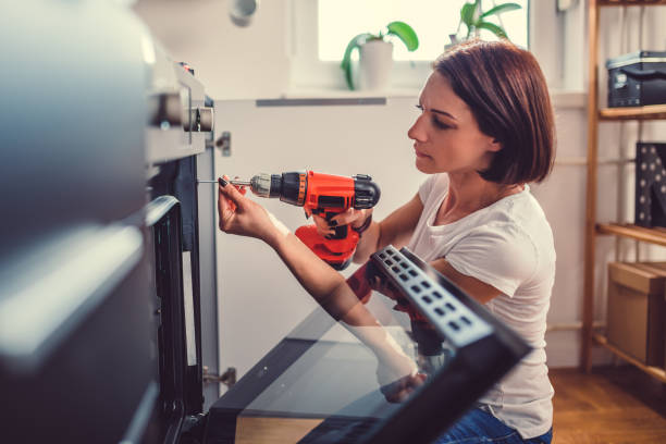 Woman using a cordless drill Woman working on a new kitchen installation and using a cordless drill drill stock pictures, royalty-free photos & images