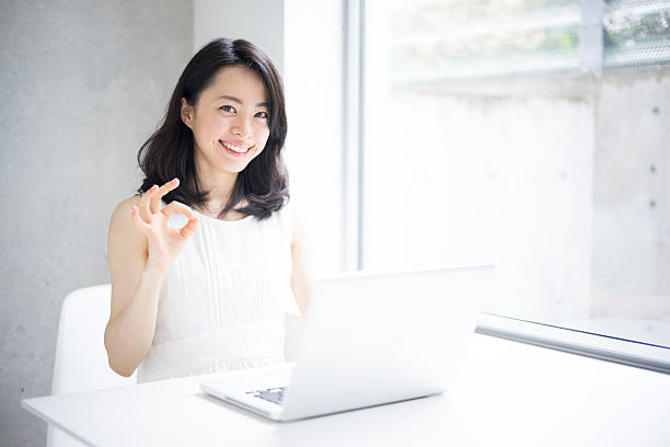 Woman using a laptop and making ok sign stock photo