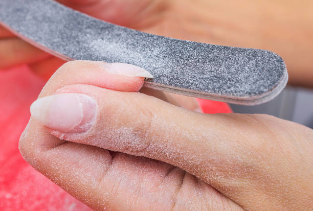Woman using a nail file removes old gel polish from her nails. Manicure at home. Selective focus, close-up. Woman using a nail file removes old gel polish from her nails. Manicure at home. Selective focus, close-up. gel nail polish stock pictures, royalty-free photos & images