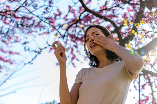 Woman Using Asthma Inhaler Outdoor Asthmatic Woman Suffers From Asthma and is Using Inhaler in the Public Park. Chronic Disease Control, Allergy Induced Asthma Remedy and Chronic Pulmonary Disease Concept. nose problem stock pictures, royalty-free photos & images