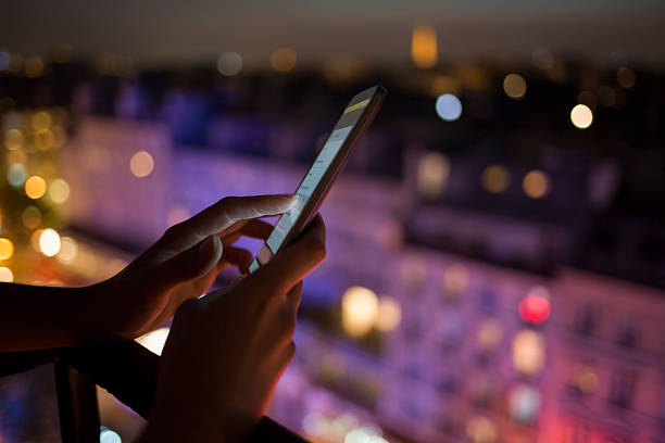 Woman using her mobile phone , city skyline night light background stock photo