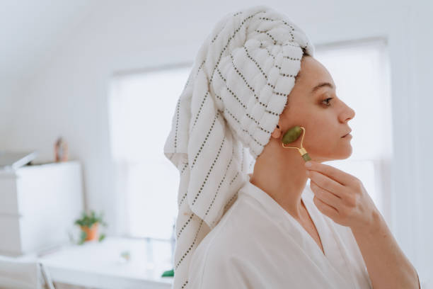Woman using jade roller on her face at home Woman using jade roller on her face at home rose quartz stock pictures, royalty-free photos & images