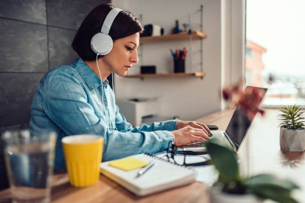 Woman using laptop and listening music on a headphones stock photo