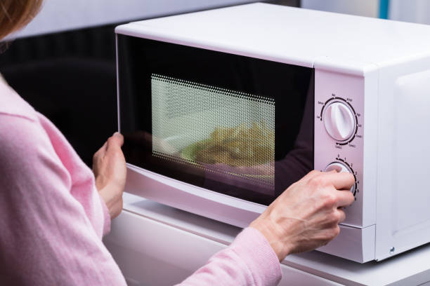 Woman Using Microwave Oven For Heating Food Close-up Of Woman Using Microwave Oven For Heating Food At Home microwave stock pictures, royalty-free photos & images