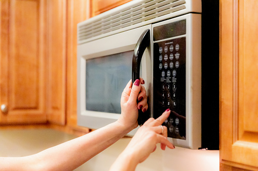 Woman programming Microwave Oven to heat the food