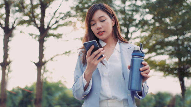 Woman using mobile phone while walking stock photo