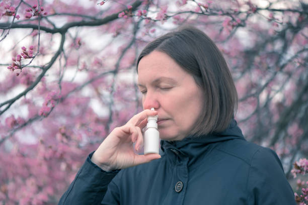 Woman using nasal spray outdoors Woman using nasal spray outdoors for tree pollen allergy treatment antihistamine stock pictures, royalty-free photos & images