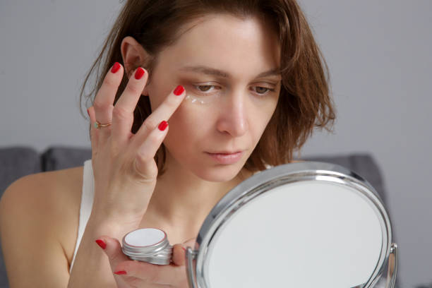 Woman using skin care products in front of the mirror at home. Domestic life, home spa, self care and pampering concept. Woman using skin care products in front of the mirror at home. Domestic life, home spa, self care and pampering concept.uns dark circles stock pictures, royalty-free photos & images
