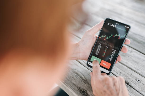 Woman using smartphone investing application to buy cryptocurrency stock photo