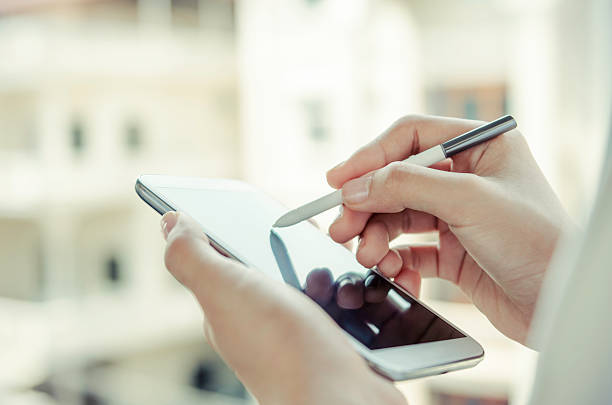 woman using tablet with stylus pen stock photo