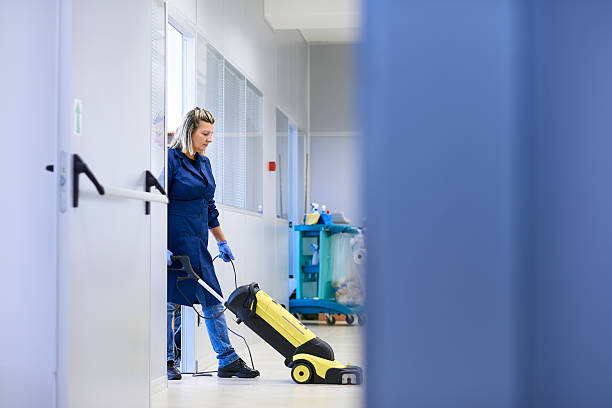 Woman vacuuming floor of office area Woman working, professional maid cleaning and washing floor with machinery in industrial building. Full length, copy space professional cleaning stock pictures, royalty-free photos & images