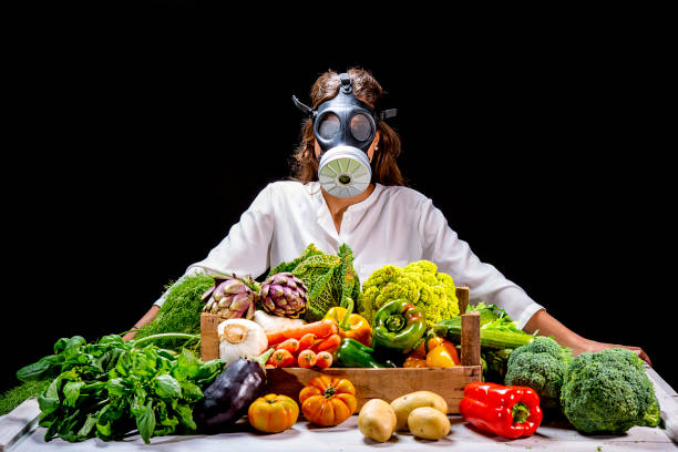 woman vegetables on table wearing gas mask on black background stock photo