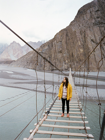 Young Caucasian woman walking on suspension bridge in Pakistan