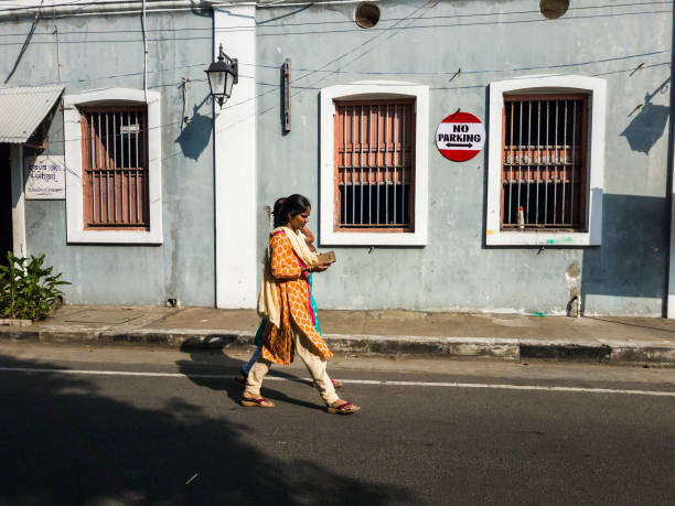 Woman walking past French architecture in Pondicherry Pondicherry. India - February 2020: An Indian woman walking past the exquisite French architecture of the city of Pondicherry. indian women walking stock pictures, royalty-free photos & images