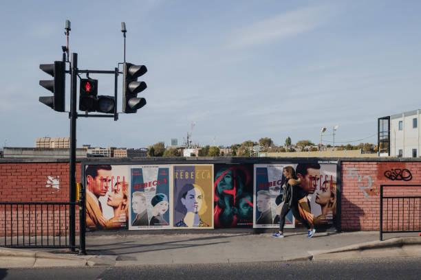 런던 풀럼에서 영화 레베카를 위해 포스터를 지나가는 여성 - fulham 뉴스 사진 이미지
