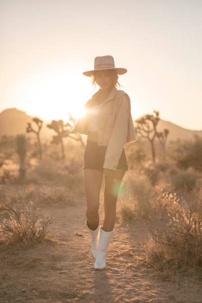 woman walking toward camera in cowboy hat and boots during golden sunset - desert cowgirl bildbanksfoton och bilder