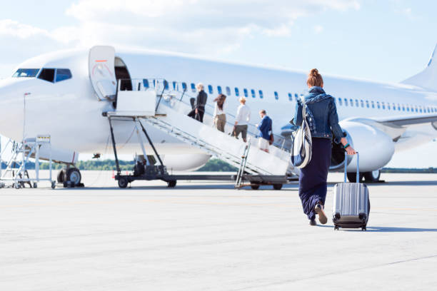 Woman walking towards the airplane Rear view of young woman with luggage walking towards the airplane. Female traveler going on vacation passenger stock pictures, royalty-free photos & images