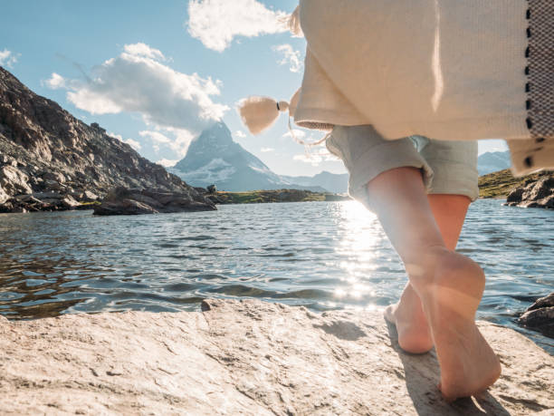 Woman walks barefoot on rock by the lake, Matterhorn in distance stock photo