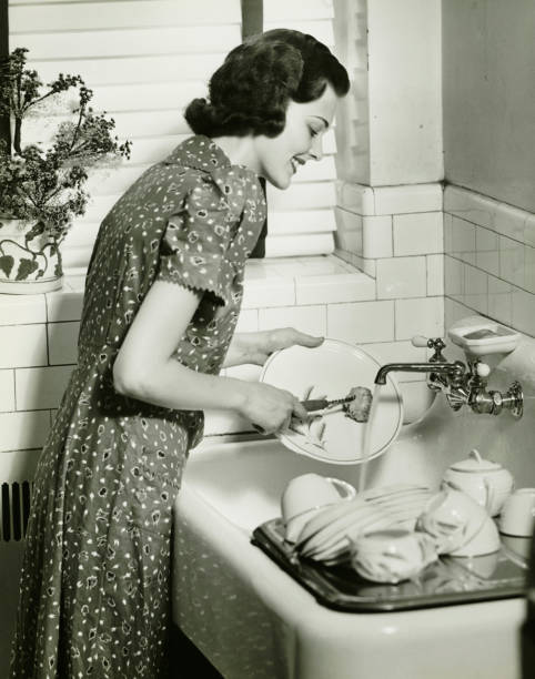 Woman washing dishes at kitchen sink, (B&W)  housewife stock pictures, royalty-free photos & images
