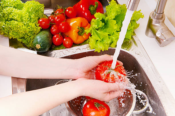 A woman washing fresh vegetables under the tap stock photo