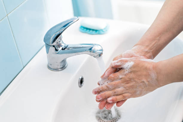 Woman washing hands with soap under the water tap stock photo