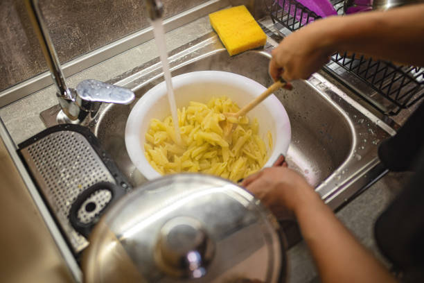 Woman washing pasta before cooking stock photo