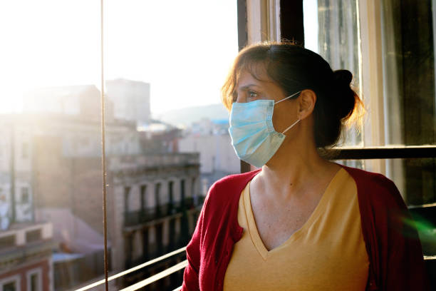 woman wearing face mask at the window stock photo