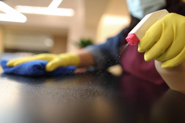 Woman wearing gloves cleaning desktop Woman wearing yellow gloves cleaning black countertop clean desk stock pictures, royalty-free photos & images