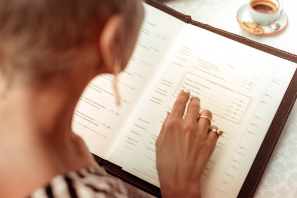 vrouw draagt mooie ringen lezen van het menu in het restaurant - menu stockfoto's en -beelden