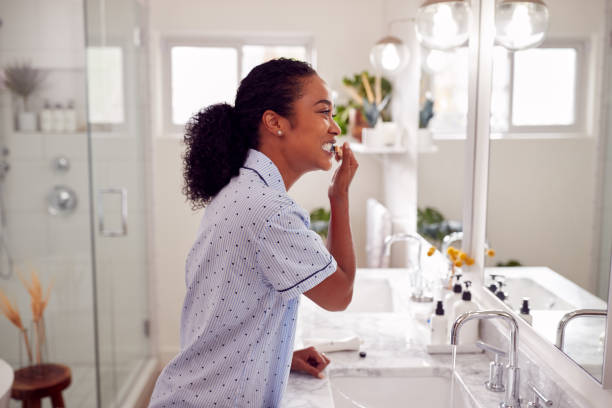 kvinna bär pyjamas stående vid handfat borsta tänderna i badrummet - kvinna borstar tänderna bildbanksfoton och bilder