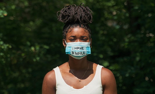 A young woman wears a face mask during global pandemic that says 