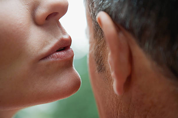 Woman whispering into man's ear  whispering stock pictures, royalty-free photos & images