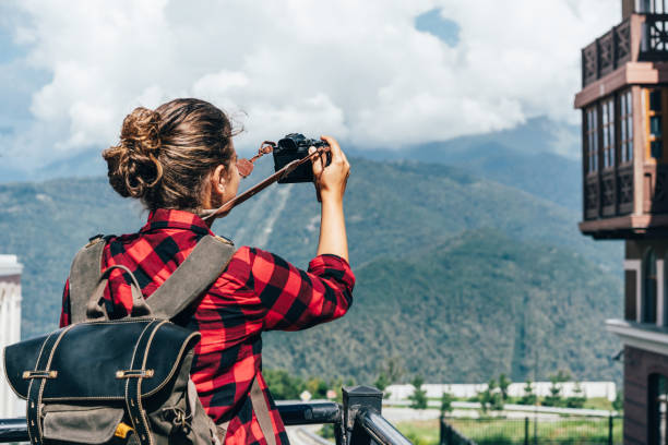 woman with a backpack takes pictures on a mountain camera. stock photo