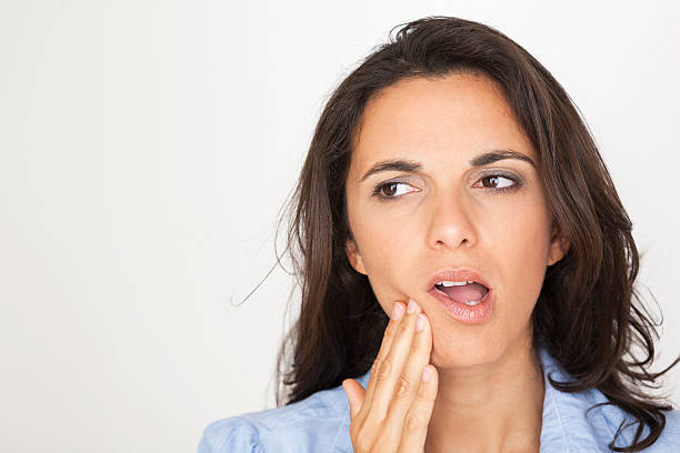 A woman with a toothache touching her mouth on white stock photo