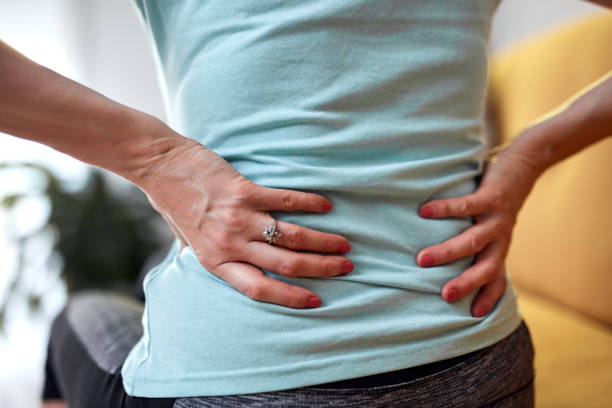 Woman with back and hip pain at home. stock photo
