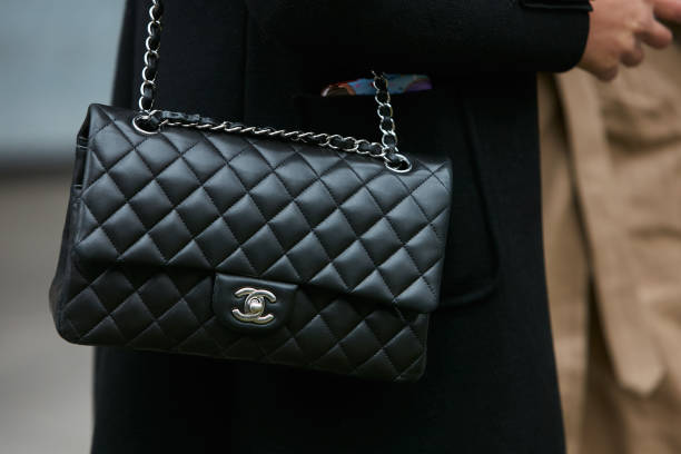 Woman with black Chanel leather bag with silver chain MILAN - JANUARY 15: Woman with black Chanel leather bag with silver chain before Giorgio Armani fashion show, Milan Fashion Week street style on January 15, 2018 in Milan. fashion week stock pictures, royalty-free photos & images
