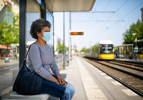 Woman wearing medical face mask commuting in a tramway train during corona virus outbreak. Female travelling in metro during Covid-19 pandemic.