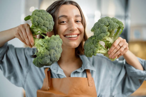 Woman with fresh broccoli on the kitchen stock photo