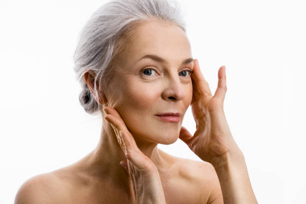 Woman with grey hair pulls the skin with her hands while demonstrating face lifting stock photo