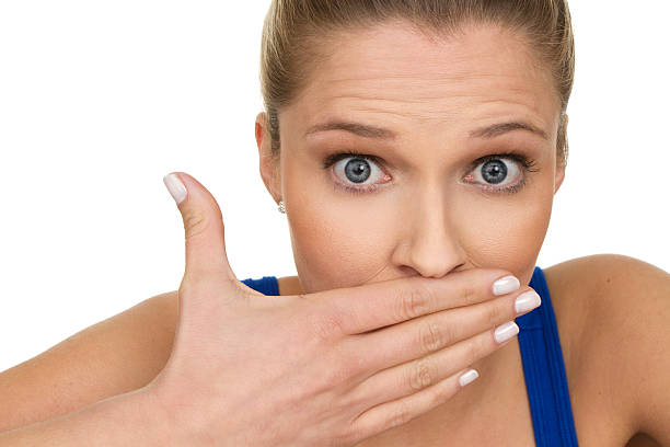 Woman with hand over mouth and surprised expression "close up of beautiful surprised woman holding her mouth, isolated on white background" bad breath stock pictures, royalty-free photos & images