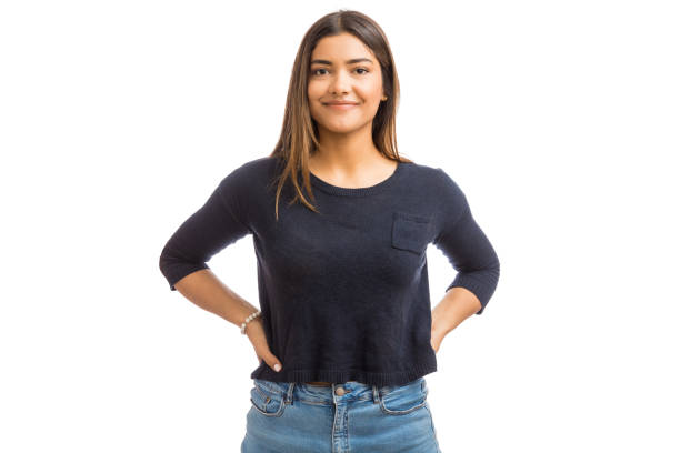 Woman With Hands On Hips In Studio Portrait of female brunette in blue top standing against white background brown hair stock pictures, royalty-free photos & images