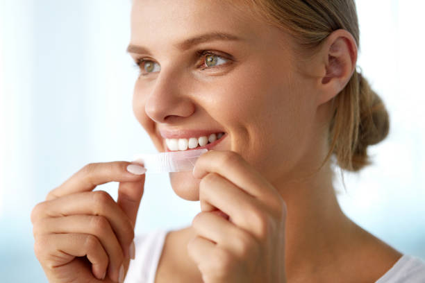 frau mit gesunde weiße zähne mit zahnweiß-streifen - zahnaufhellung stock-fotos und bilder