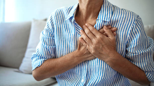 kvinna med hjärtinfarkt som håller och masserar hennes bröst - medelålders kvinna bröstsmärtor bildbanksfoton och bilder