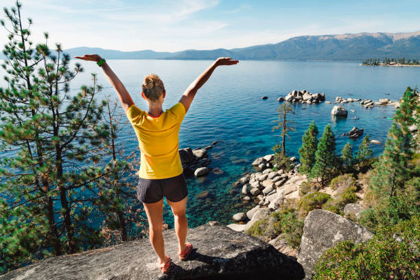 Woman with her hands in the air, standing on the shore of Lake Tahoe Young women, backpacking trough the USA, standing on the shore of Lake Tahoe. Lake Tahoe is a large freshwater lake in the Sierra Nevada of the United States. Lake Tahoe is the largest alpine lake in North America. Lake Tahoe is a major tourist attraction in both Nevada and California. It is home to winter sports, summer outdoor recreation, and scenery enjoyed throughout the year. Snow and ski resorts are a significant part of the area's economy and reputation. Lake Tahoe stock pictures, royalty-free photos & images