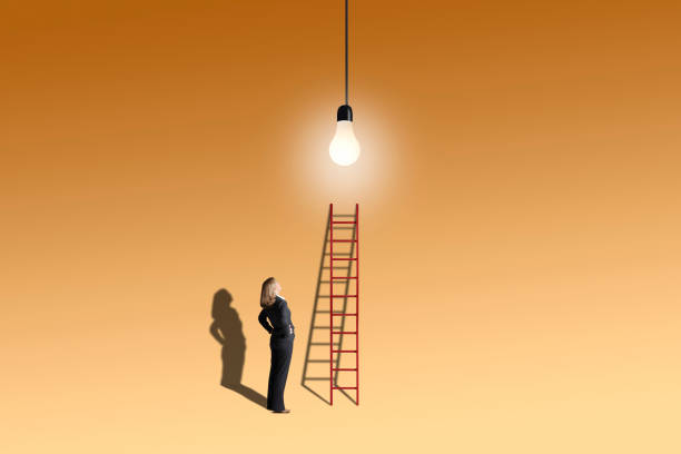 Woman With Ladder Looks Up At Light Bulb stock photo