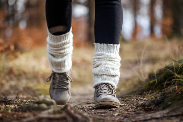 Woman with leg warmers walking on footpath in woodland Woman walking on footpath in forest. Knitted leg warmers on hiking boot Leg Warmers: stock pictures, royalty-free photos & images