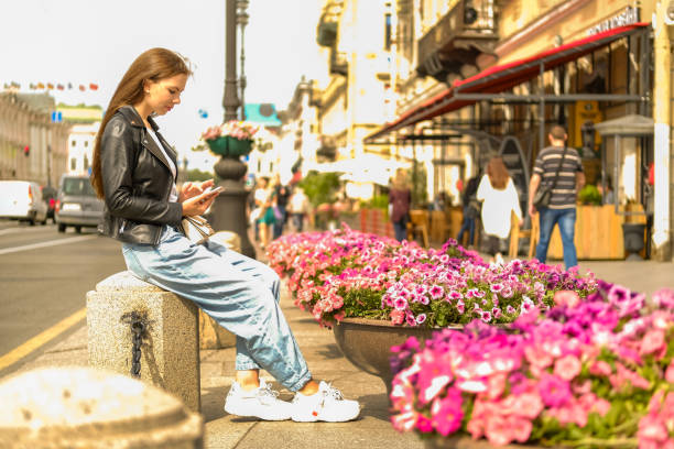 Woman with long hair sitting in the center of the city taking selfie. stock photo